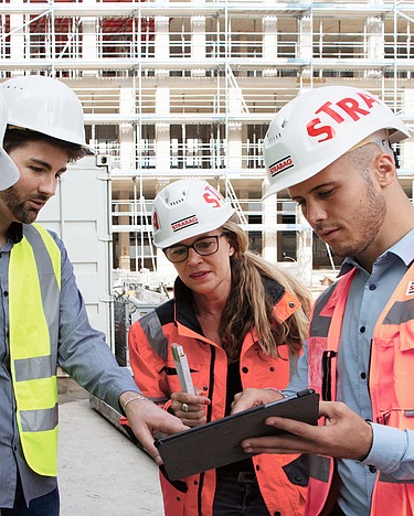 STRABAG und Lieferanten auf Baustelle mit Tablet